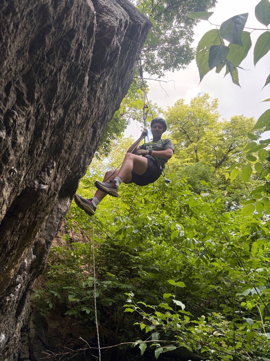 Rappelling beside a forest rock face